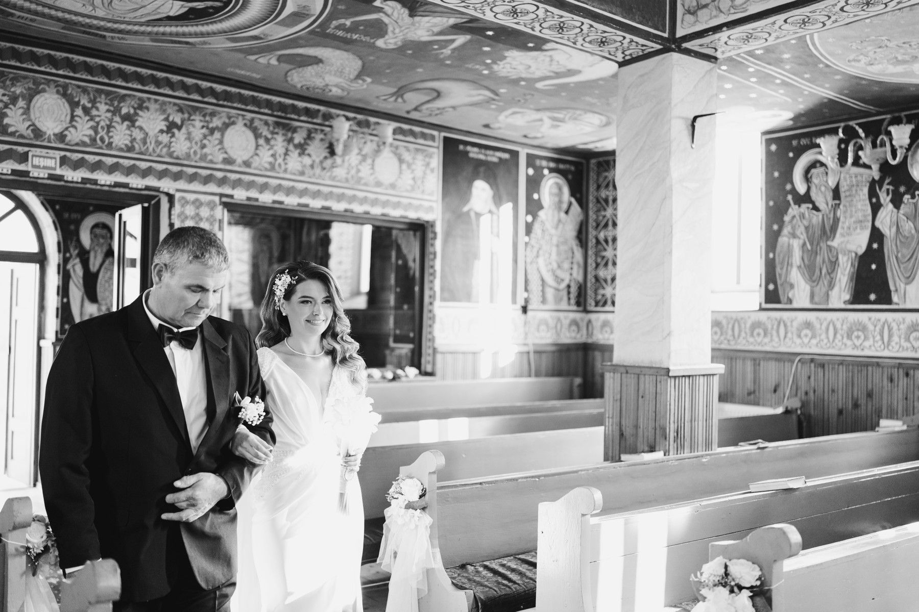 Tatăl o conduce pe mireasă spre altar, prin biserica pictată